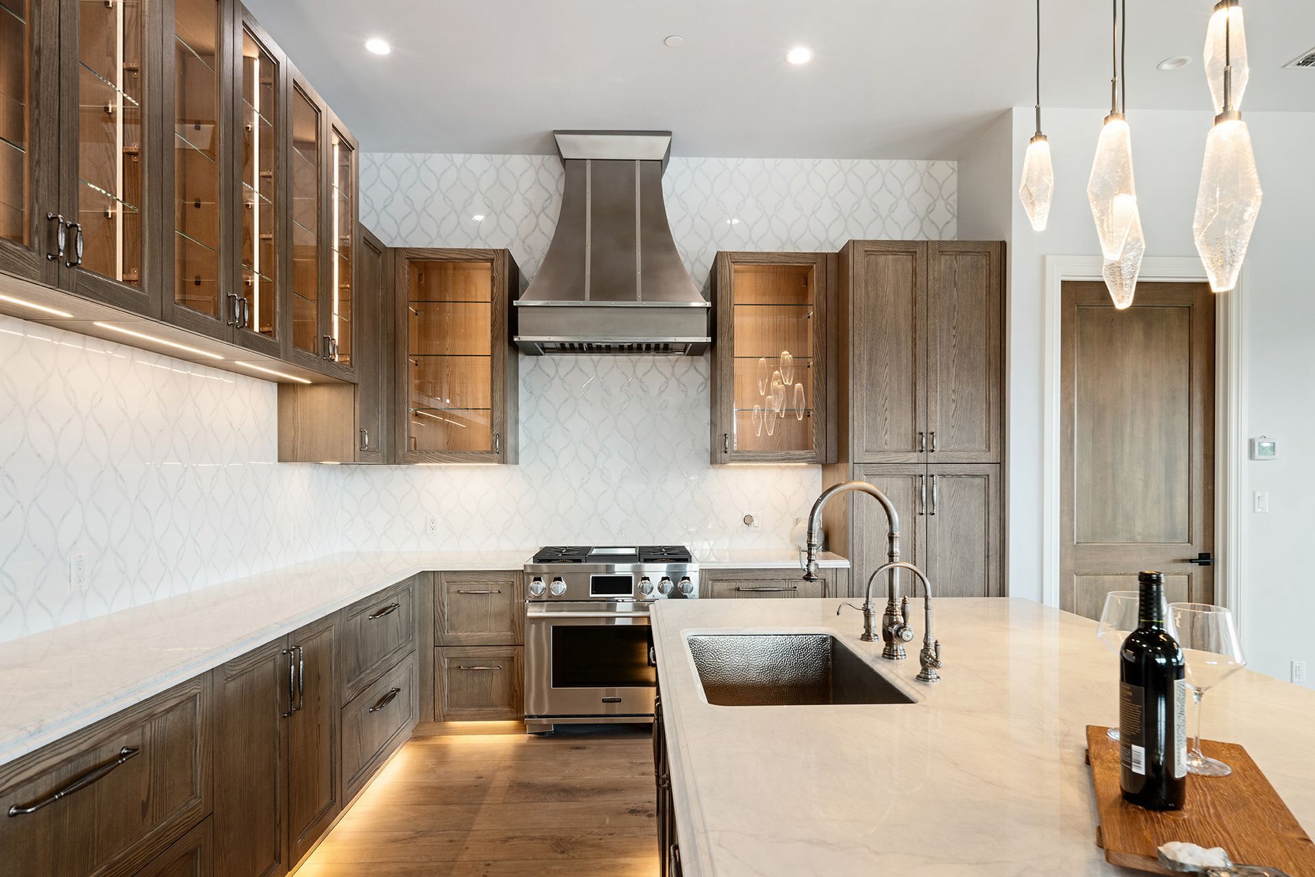 A modern kitchen with wooden cabinets, white countertops, and a stainless steel range hood.