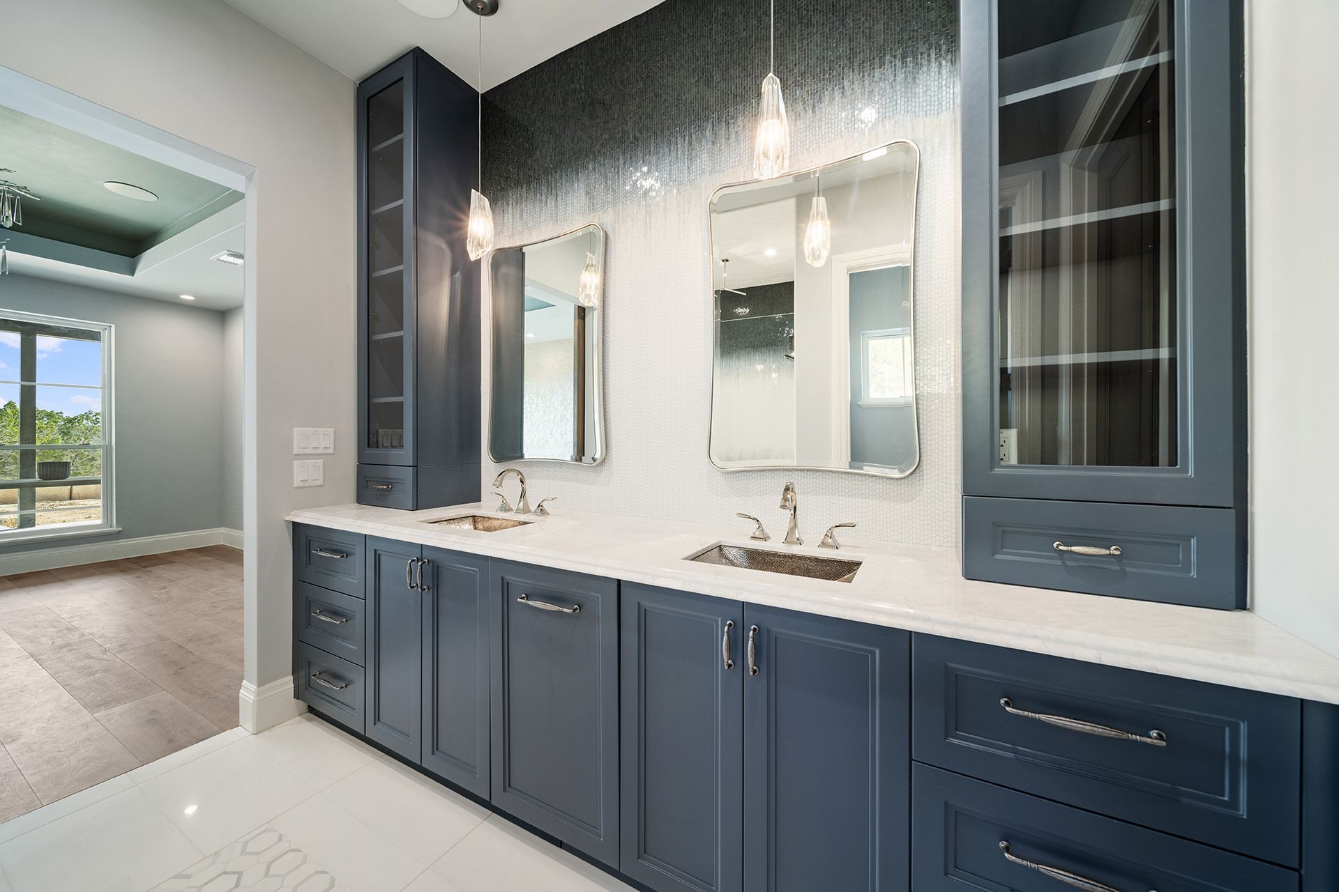Modern bathroom with navy blue vanity, white countertops, two mirrors, and built-in cabinets.