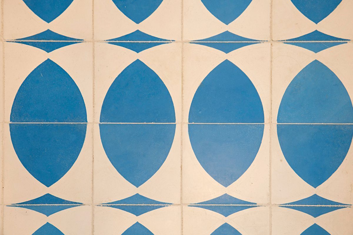 Blue and white patterned tile design; large blue ovals alternate with smaller diamond shapes against a white background.