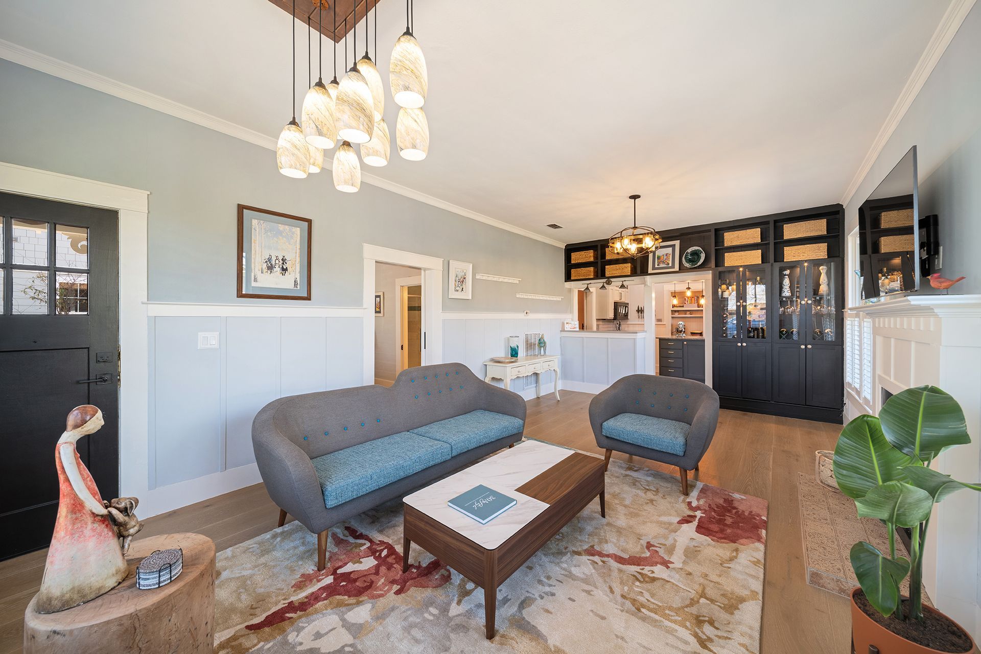 Living room with gray sofa and armchair, coffee table on a patterned rug, and modern light fixtures.