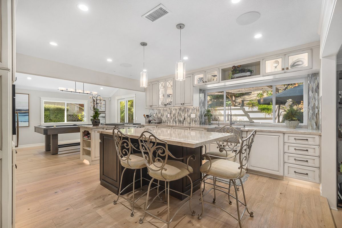 A kitchen with a large island , dining table and chairs.