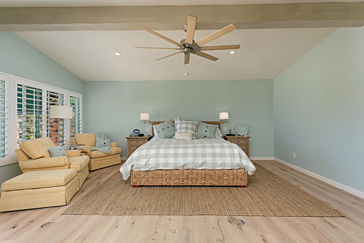 A bedroom with a large bed and a ceiling fan.