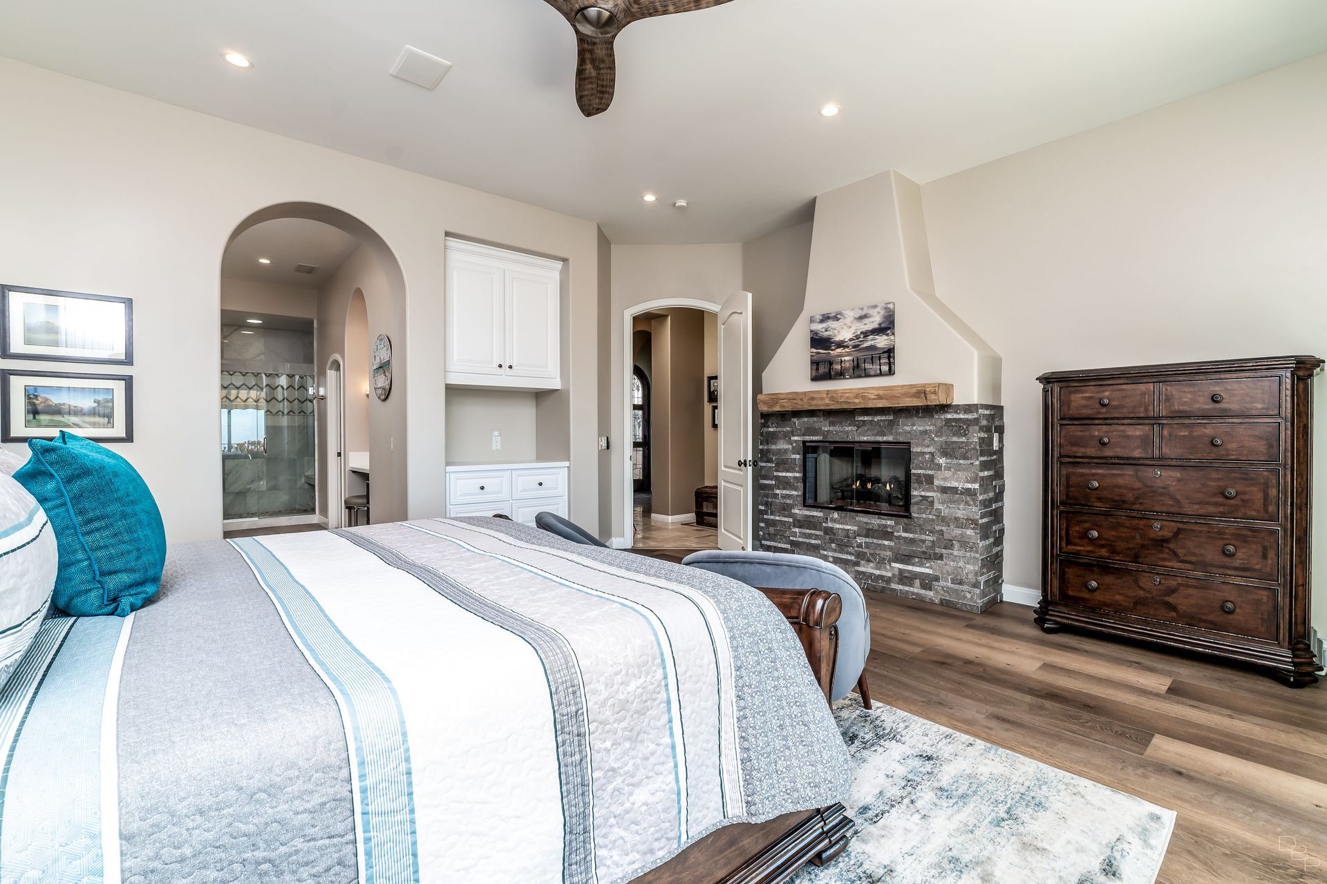 A bedroom with a large bed , dresser and fireplace.
