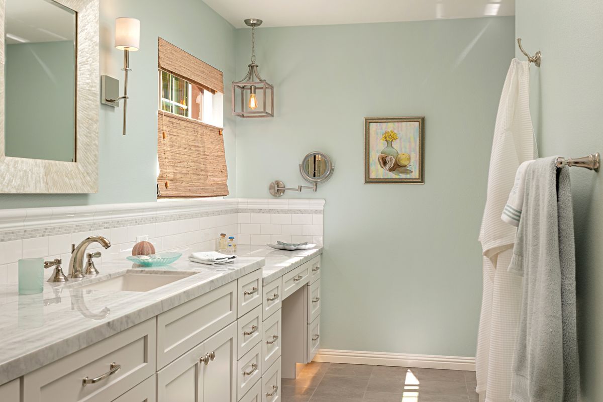 A bathroom with two sinks , a mirror , and a window.