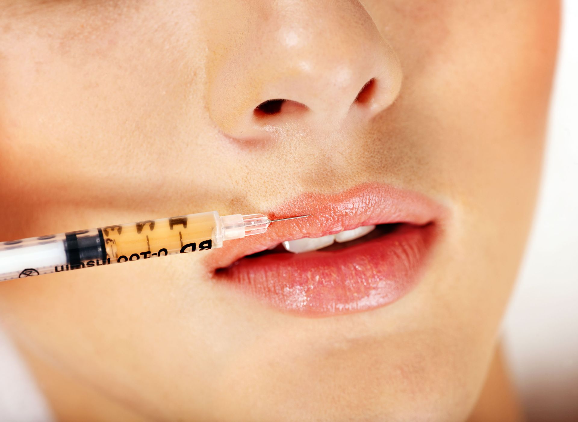 Lip gloss applicator applying peach color to a person’s lips