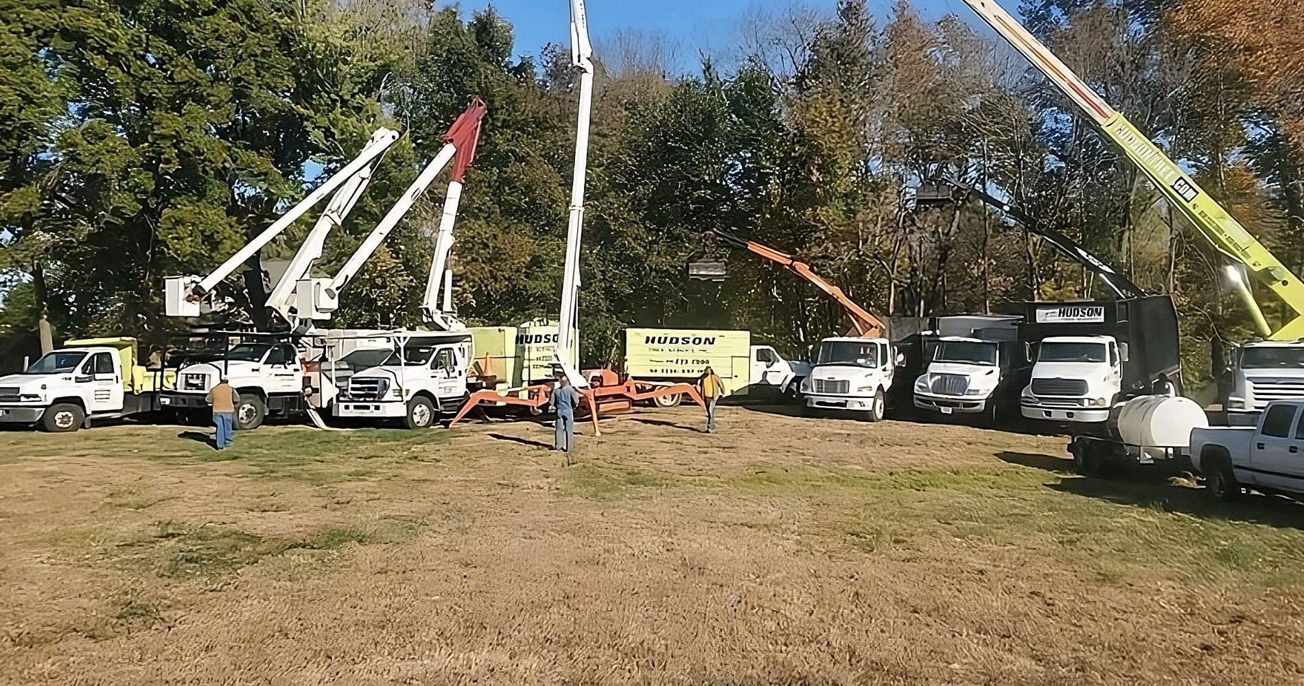 Crews with several trucks and machinery working outdoors.