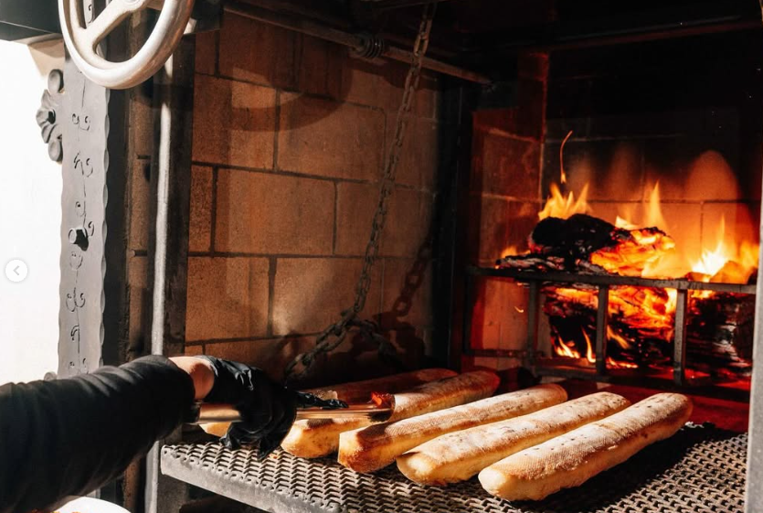A person is cooking bread in a fireplace.