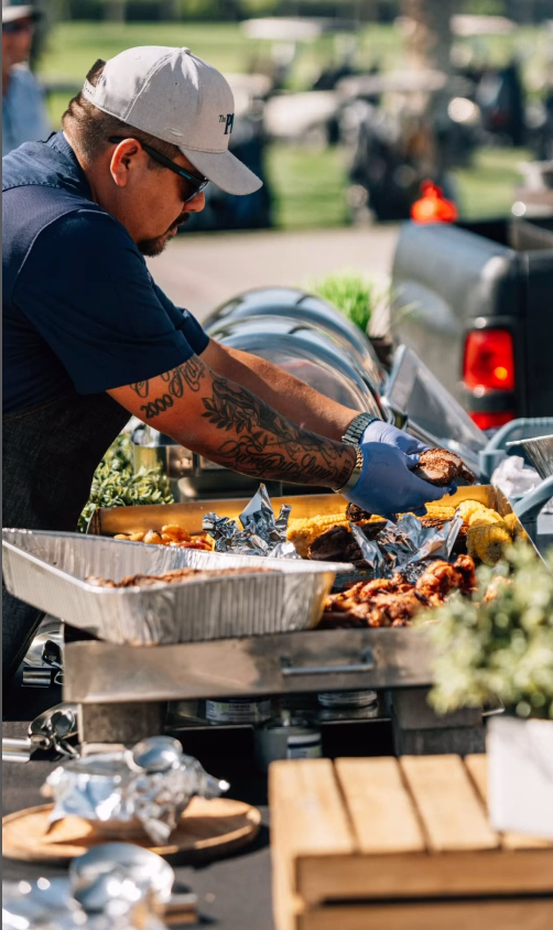 A man is standing at a table preparing food.