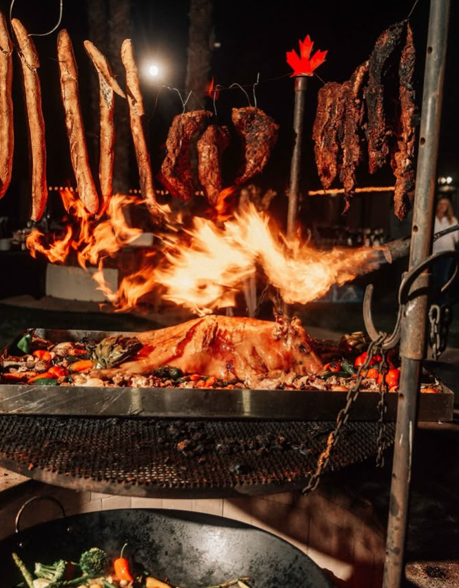 A bunch of food is cooking on a grill with a maple leaf in the background.