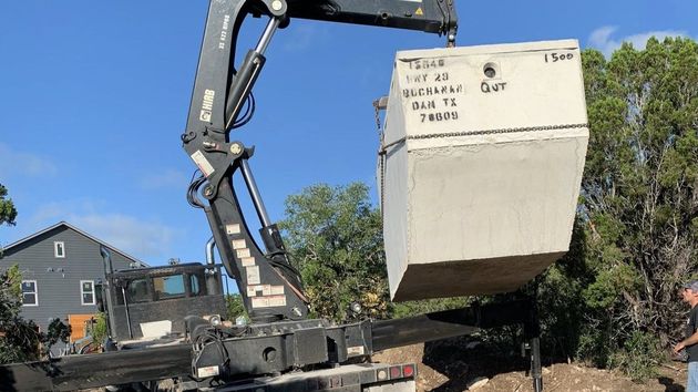 Two round plastic septic tanks, one with a red lid and one with a green lid, installed in a dirt trench outdoors.