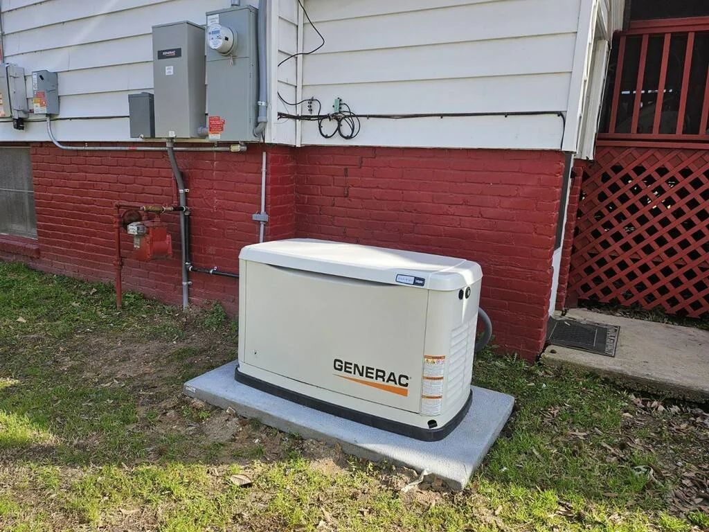 Home standby generator beside a house with utility meters and red brick foundation