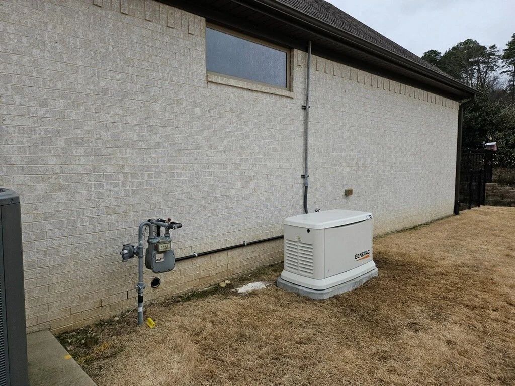 White utility enclosure and gas meter beside a gray building on dry grass.