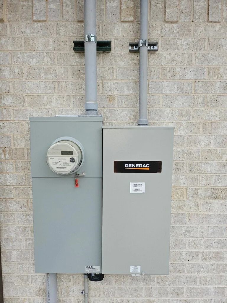 Two gray electrical meter and breaker panels mounted on a brick wall
