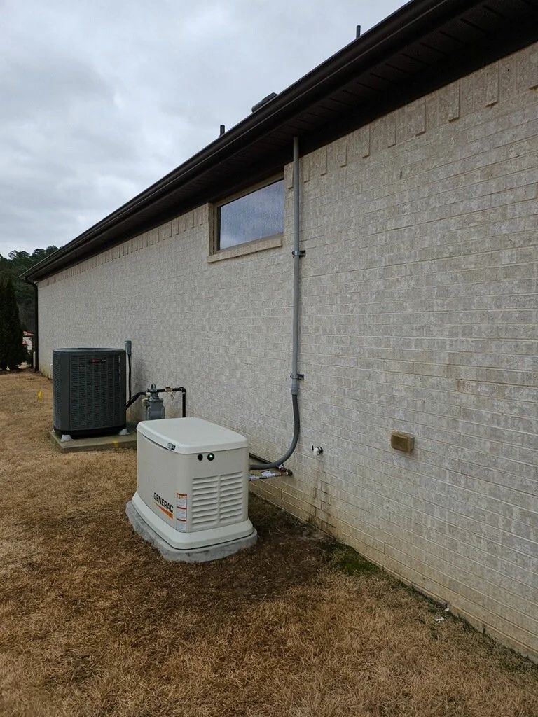 Outdoor side view of a house with an air conditioner unit and heat pump on dry grass under cloudy skies