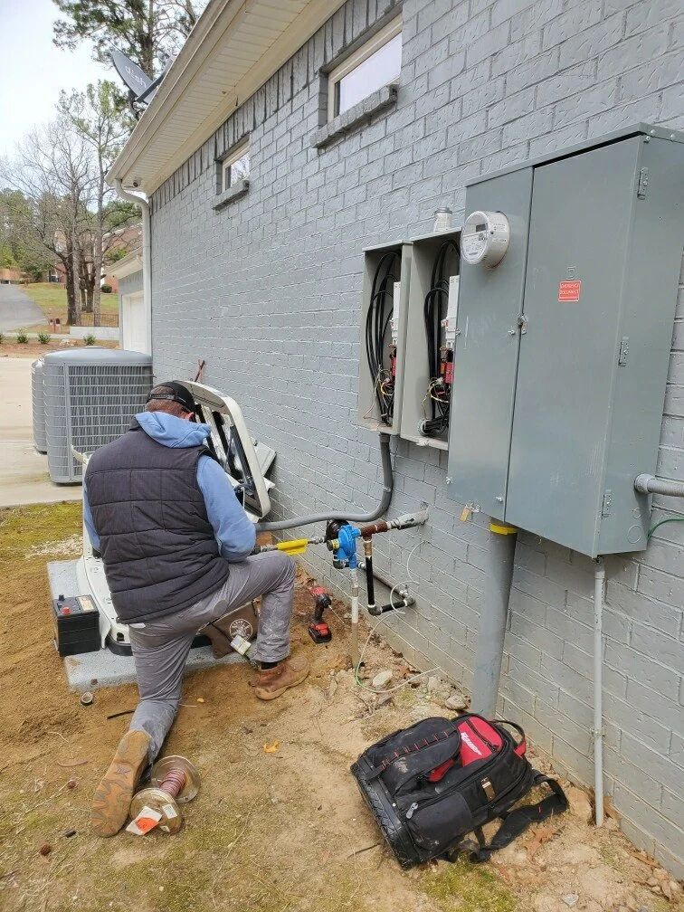 Worker kneeling beside exposed electrical wiring on a gray brick building exterior