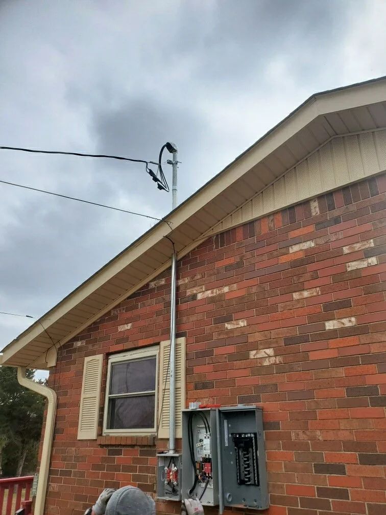 Brick house exterior with utility meter, overhead wires, and cloudy sky