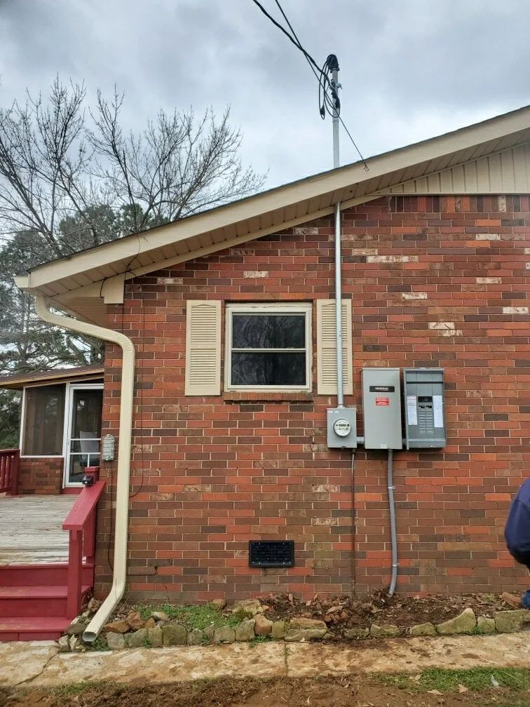 Brick house exterior with utility meters, a small window, and a red porch railing