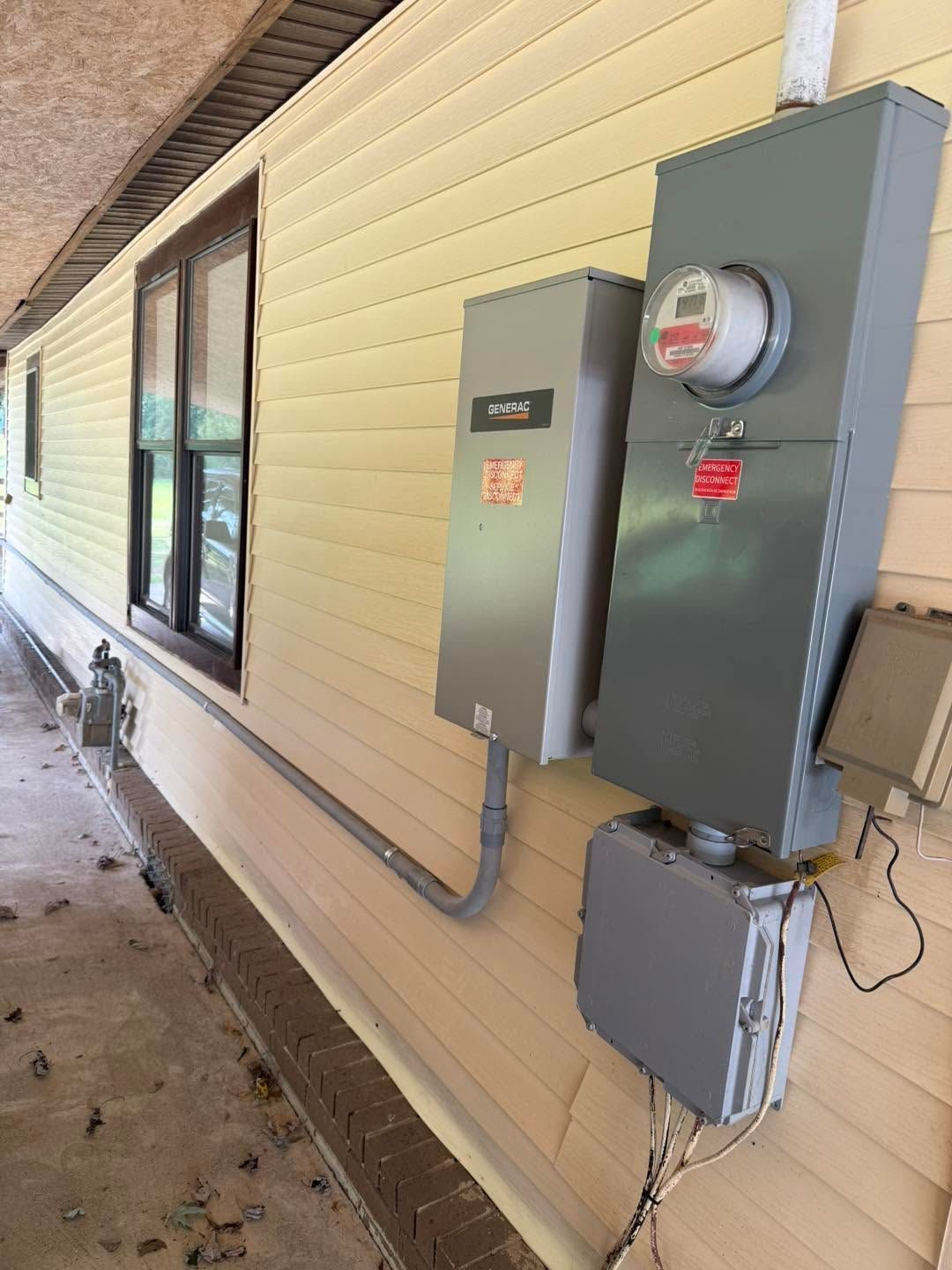 House exterior with two gray electrical meter boxes mounted on a beige wall, beside a window.