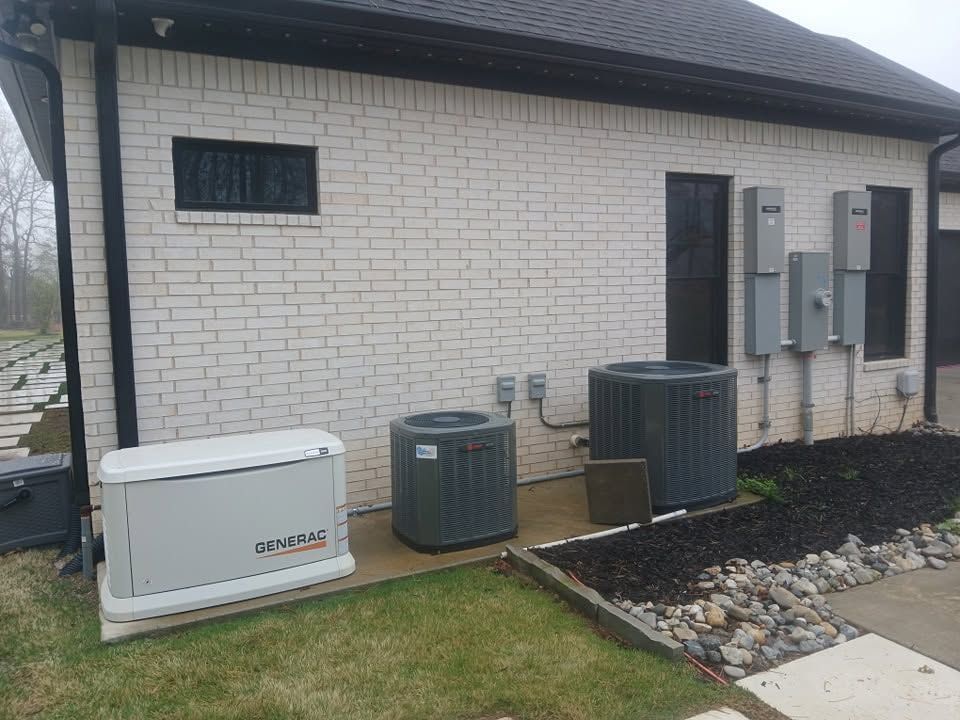 Exterior of a brick house with air conditioning units, utility boxes, and a landscaped rock border