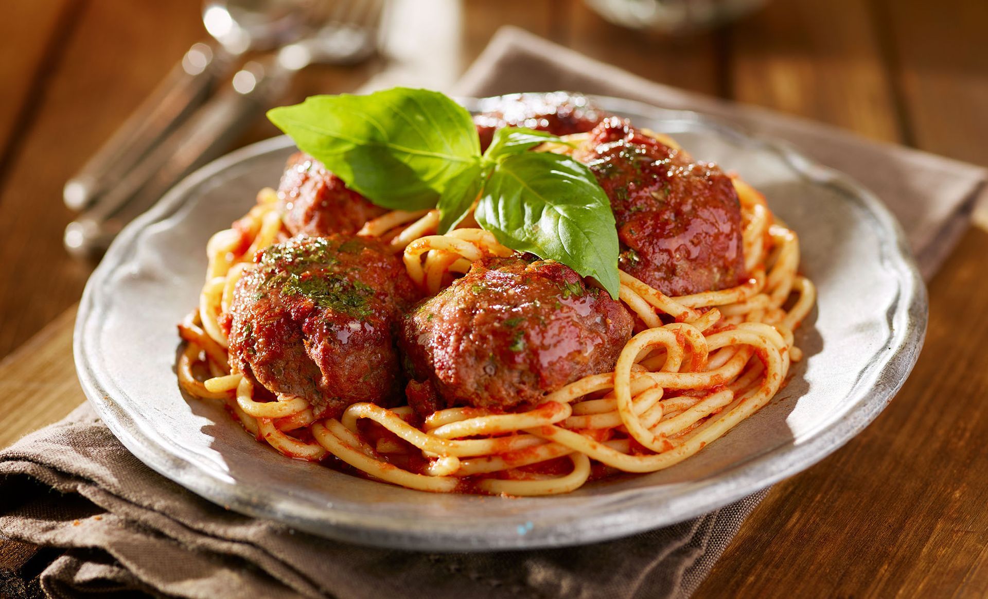 A plate of spaghetti and meatballs on a wooden table.