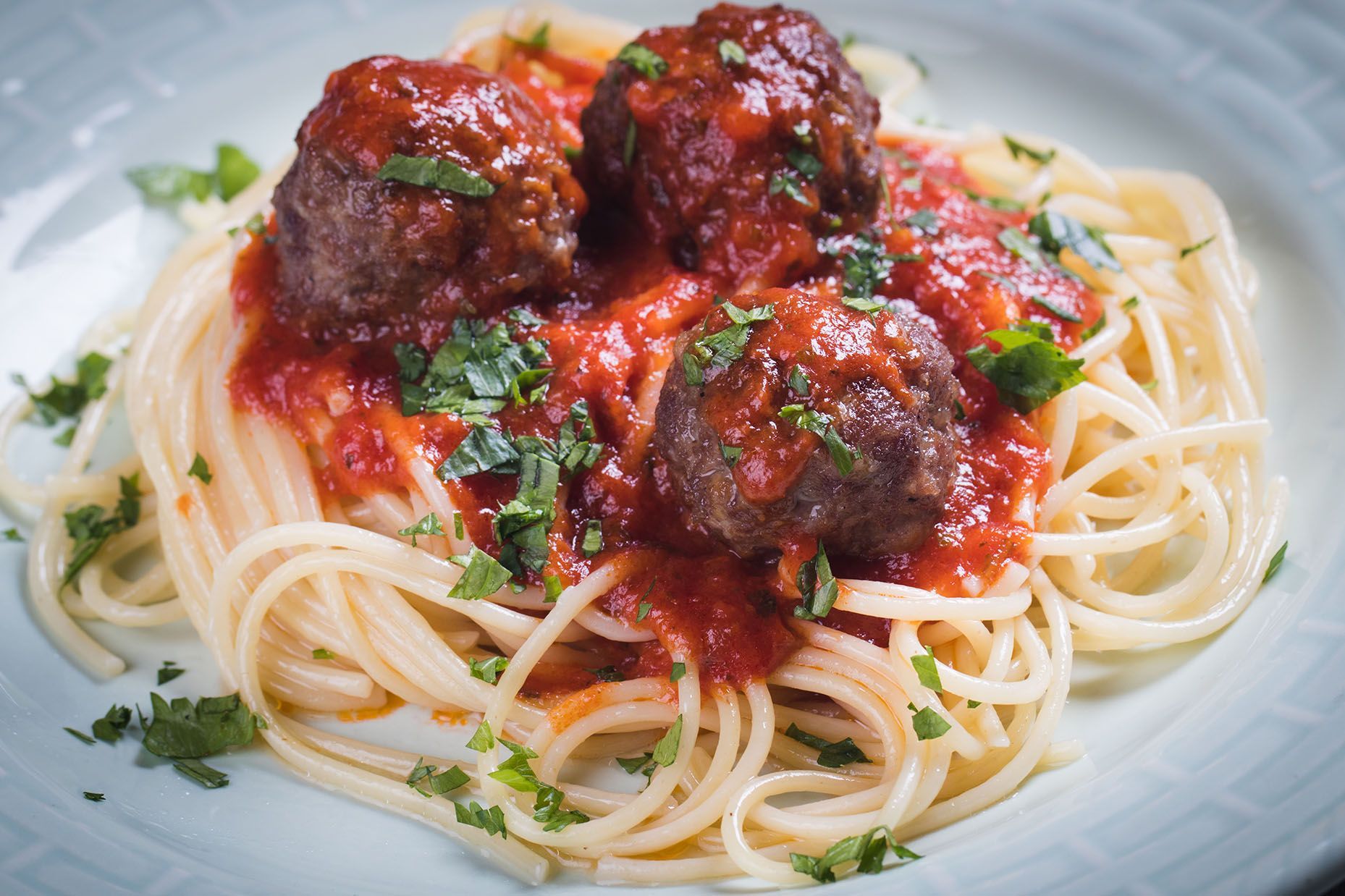A plate of spaghetti and meatballs with sauce on a table.