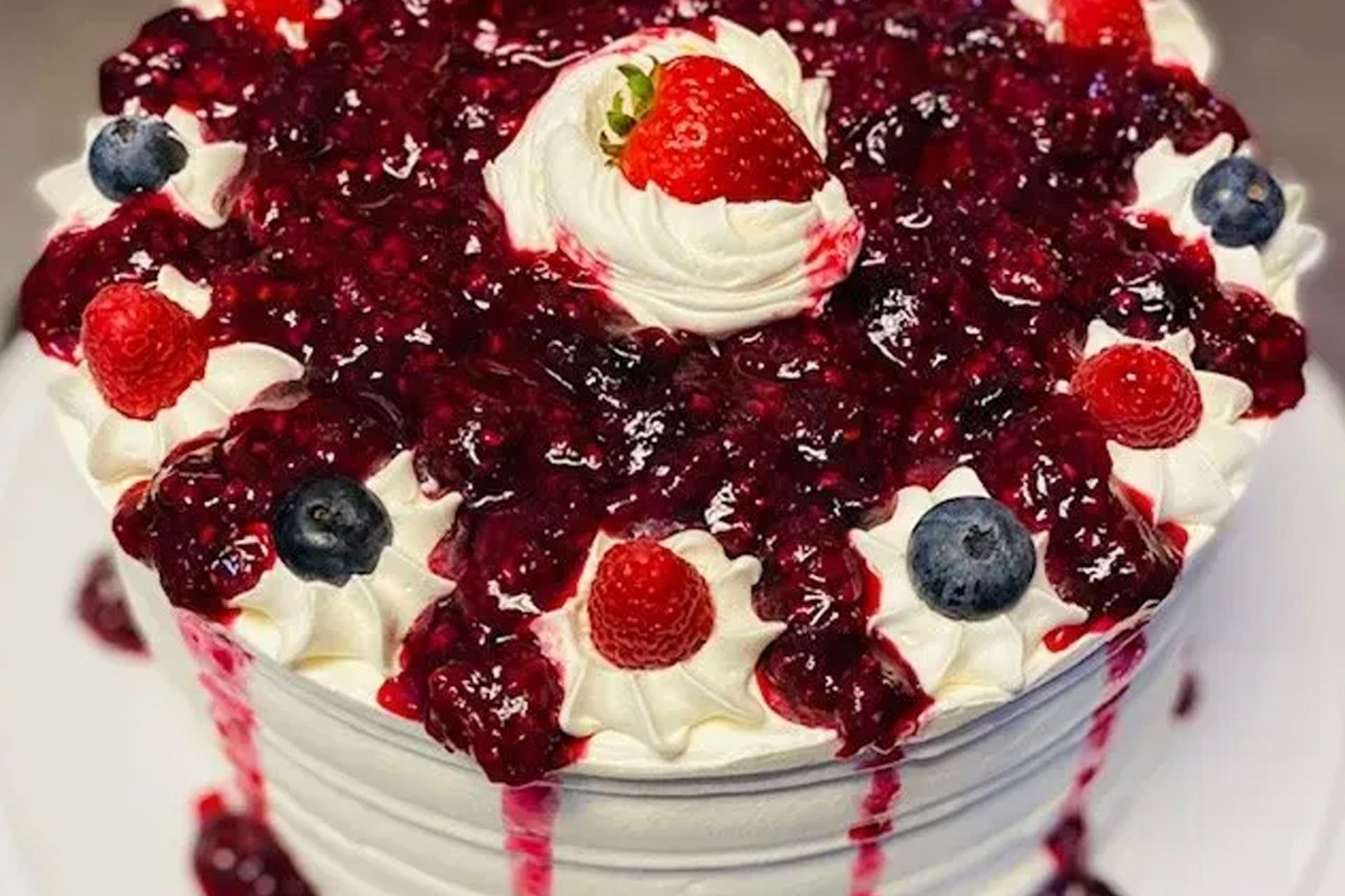 A cake with berries and whipped cream on top