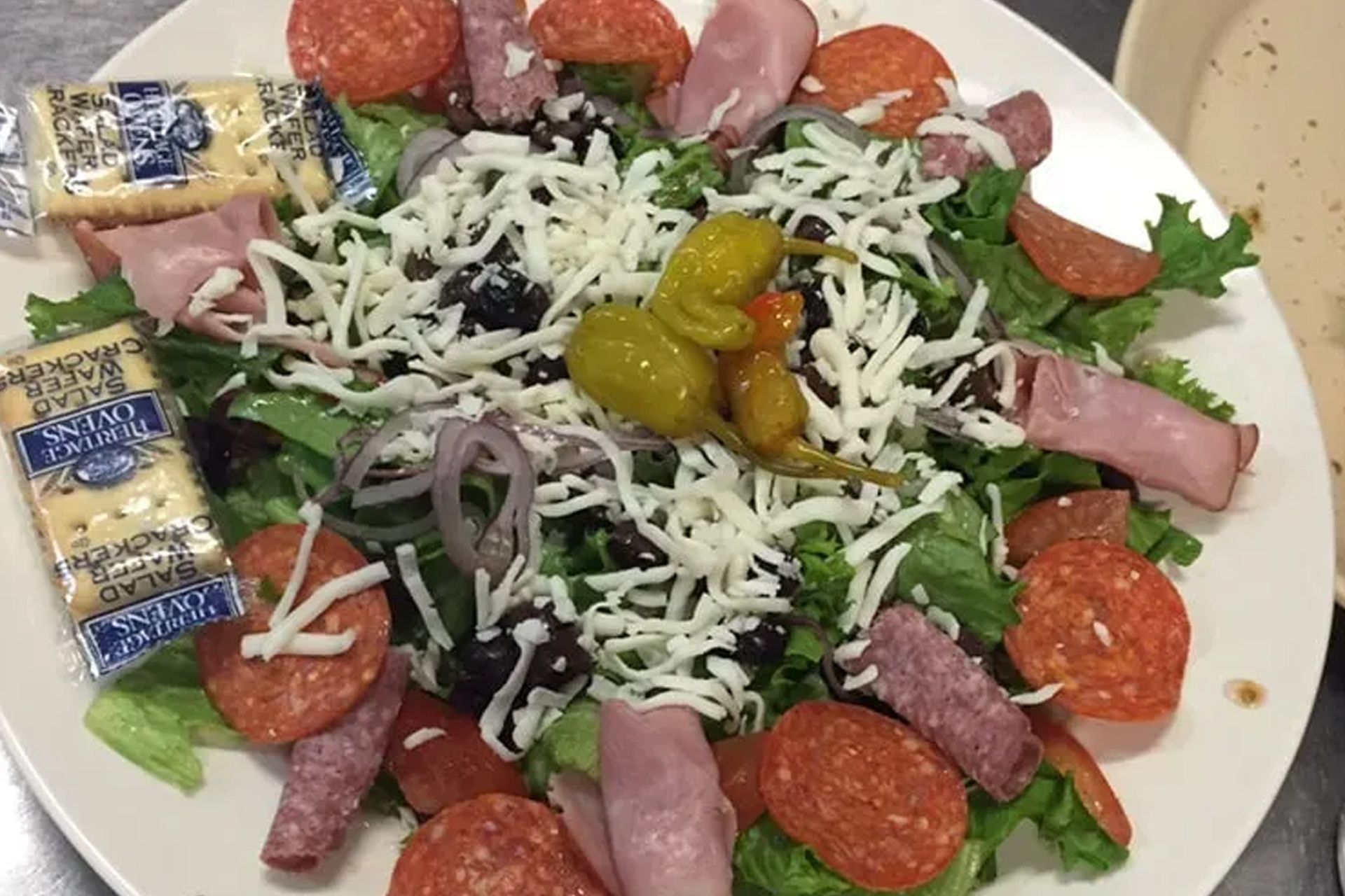 A white plate topped with a salad with pepperoni and cheese