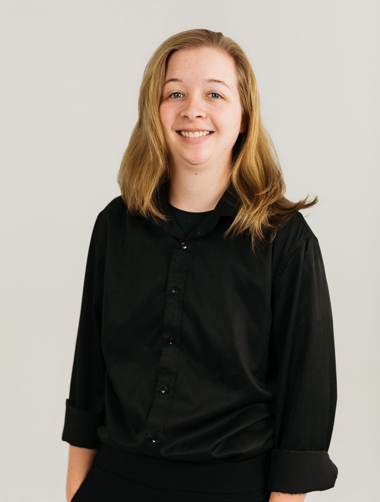 Smiling person in a black shirt against a light gray background
