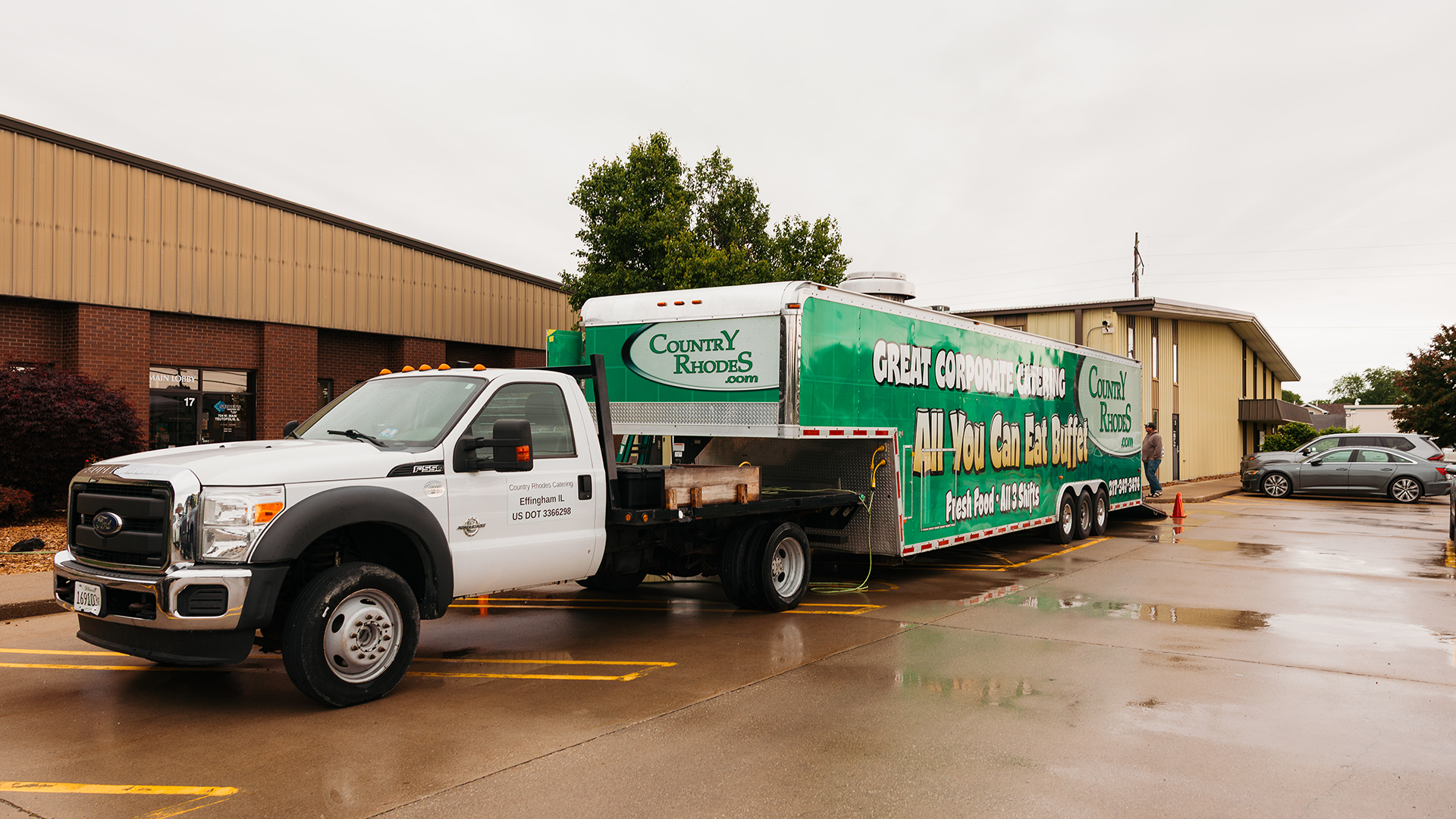 Green-and-white moving truck parked outside a building on a rainy day.