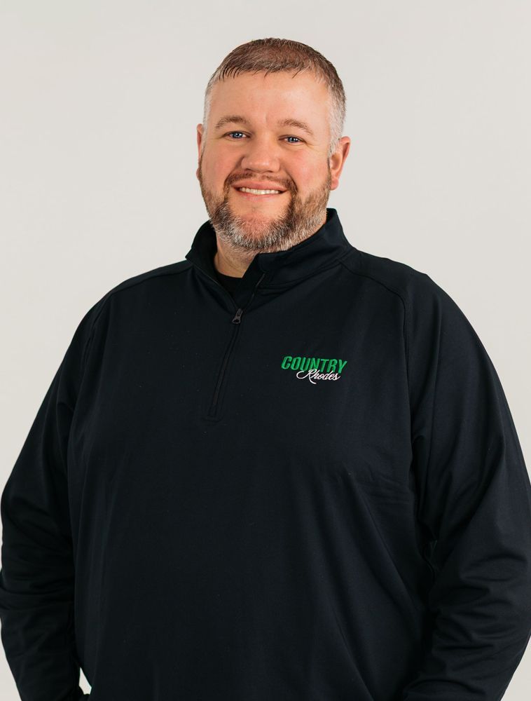 Smiling person in a black quarter-zip pullover with green logo on a light background