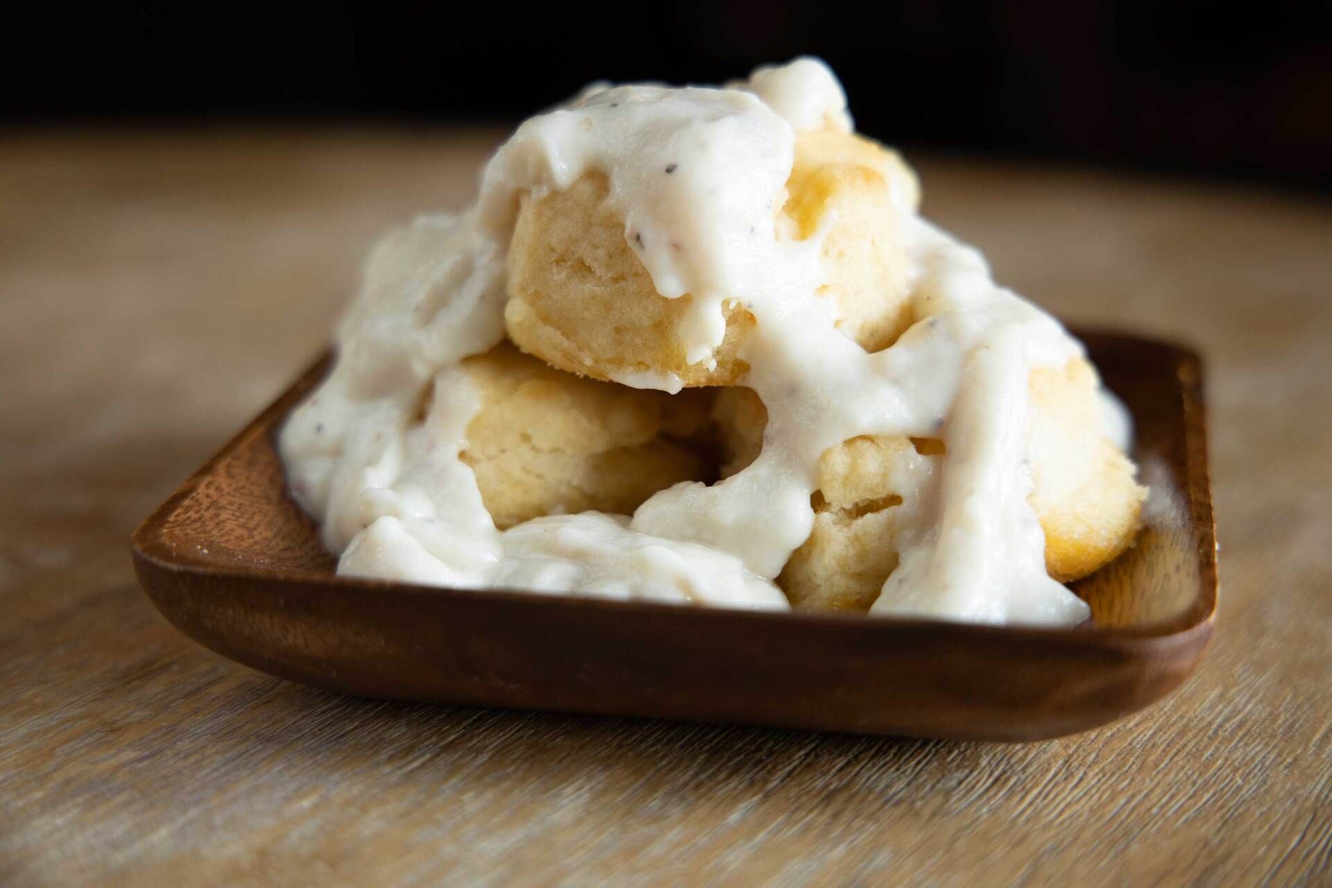 White rice crackers piled in a brown square dish on a wooden surface
