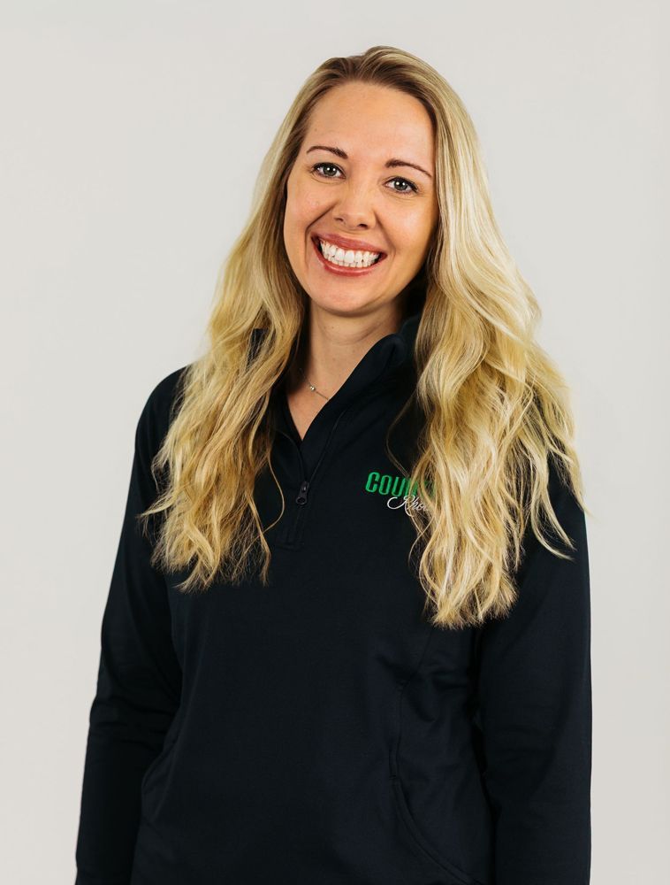 Smiling blonde woman in a black collared shirt against a light gray background