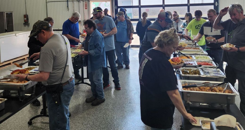 People serving themselves at buffet tables in a bright indoor cafeteria