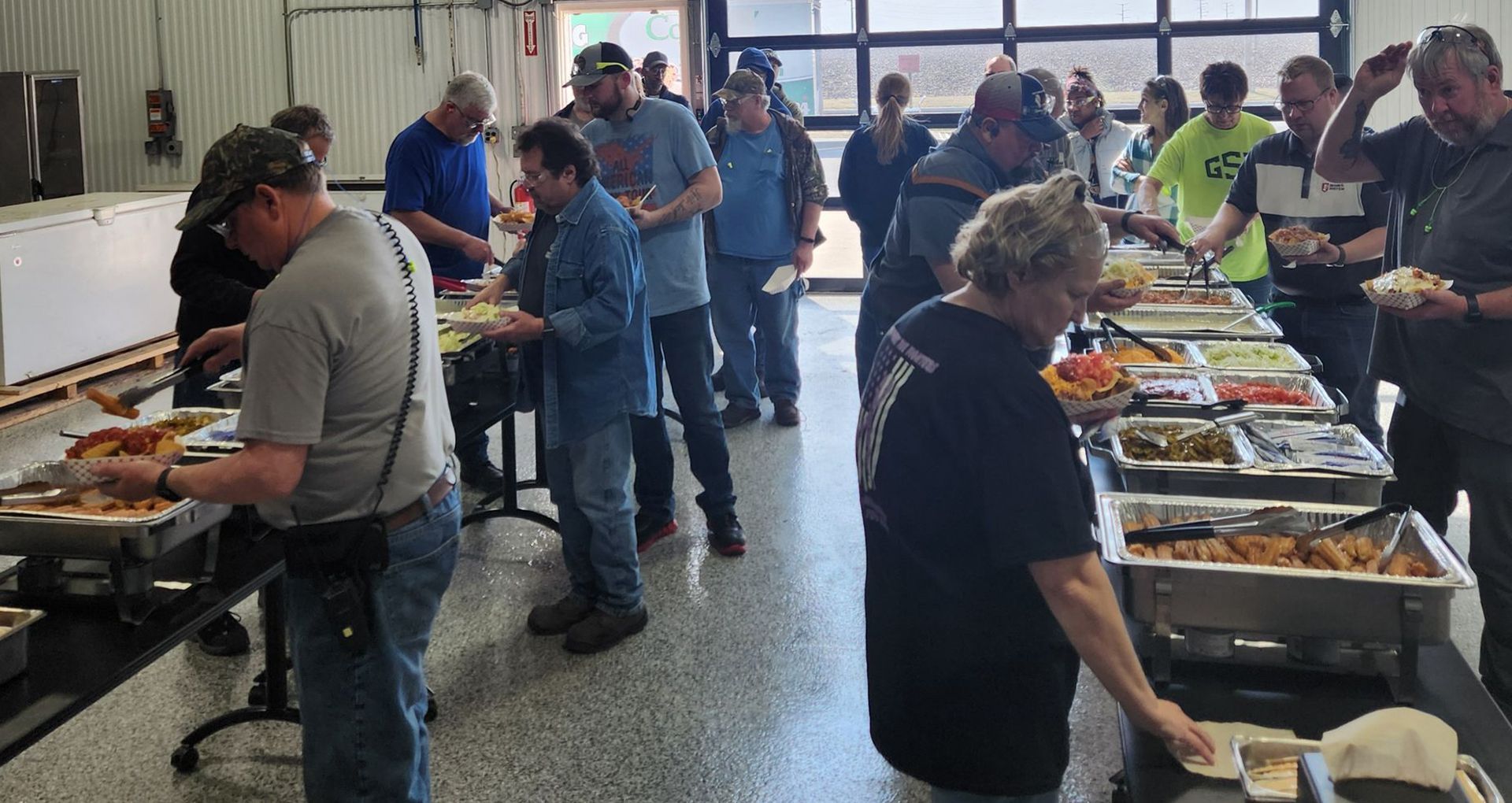 People serving themselves at buffet tables in a bright indoor cafeteria