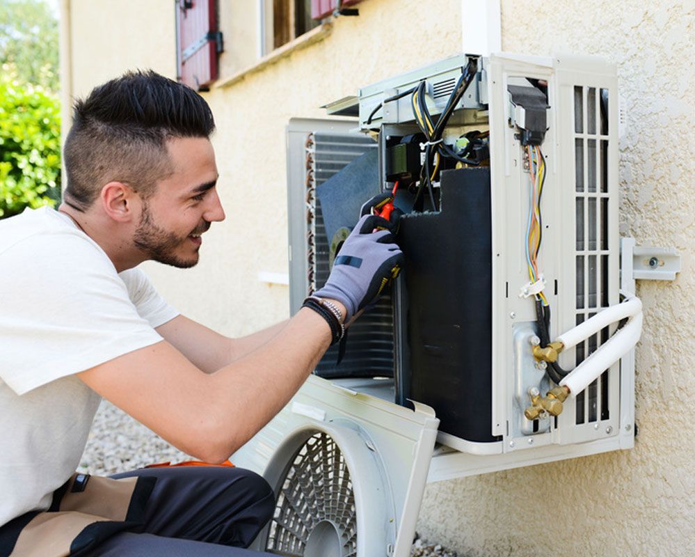 Technician repairing outdoor air conditioner unit with tools beside a house wall