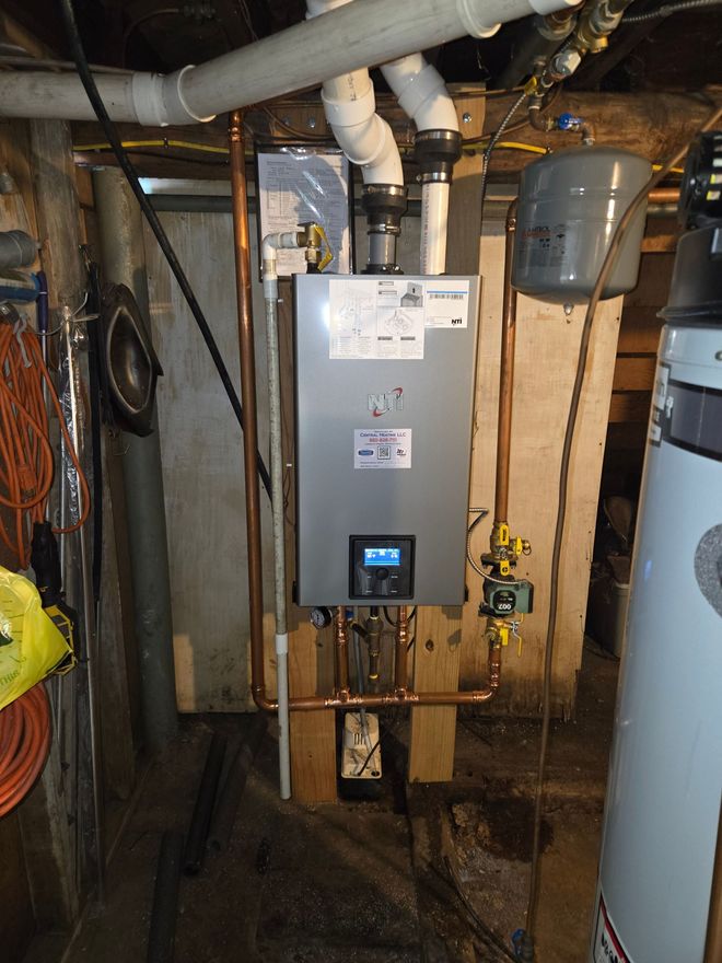 Basement utility area with a wall-mounted tankless water heater and pipes.