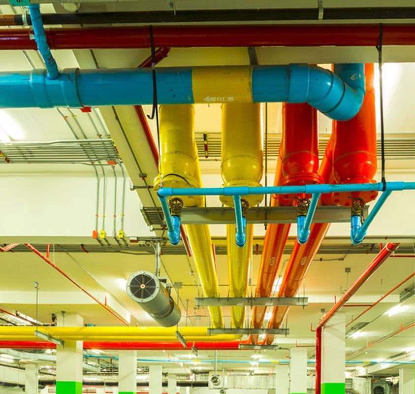 Colorful industrial ceiling pipes and ducts in blue, yellow, and red inside a utility room