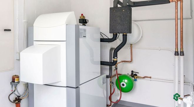 White boiler and plumbing pipes in a utility room, with green pump and wall-mounted equipment