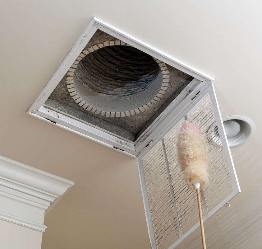 Open attic hatch in ceiling with a long duster reaching up inside.