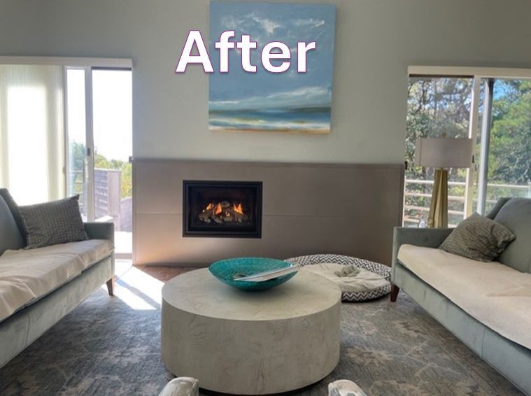 Living room after renovation, with fireplace, two sofas, round coffee table, and abstract painting.