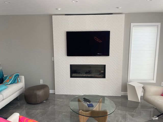 Living room with a fireplace and mounted TV on a white patterned wall, grey tiled floor, and modern furniture.