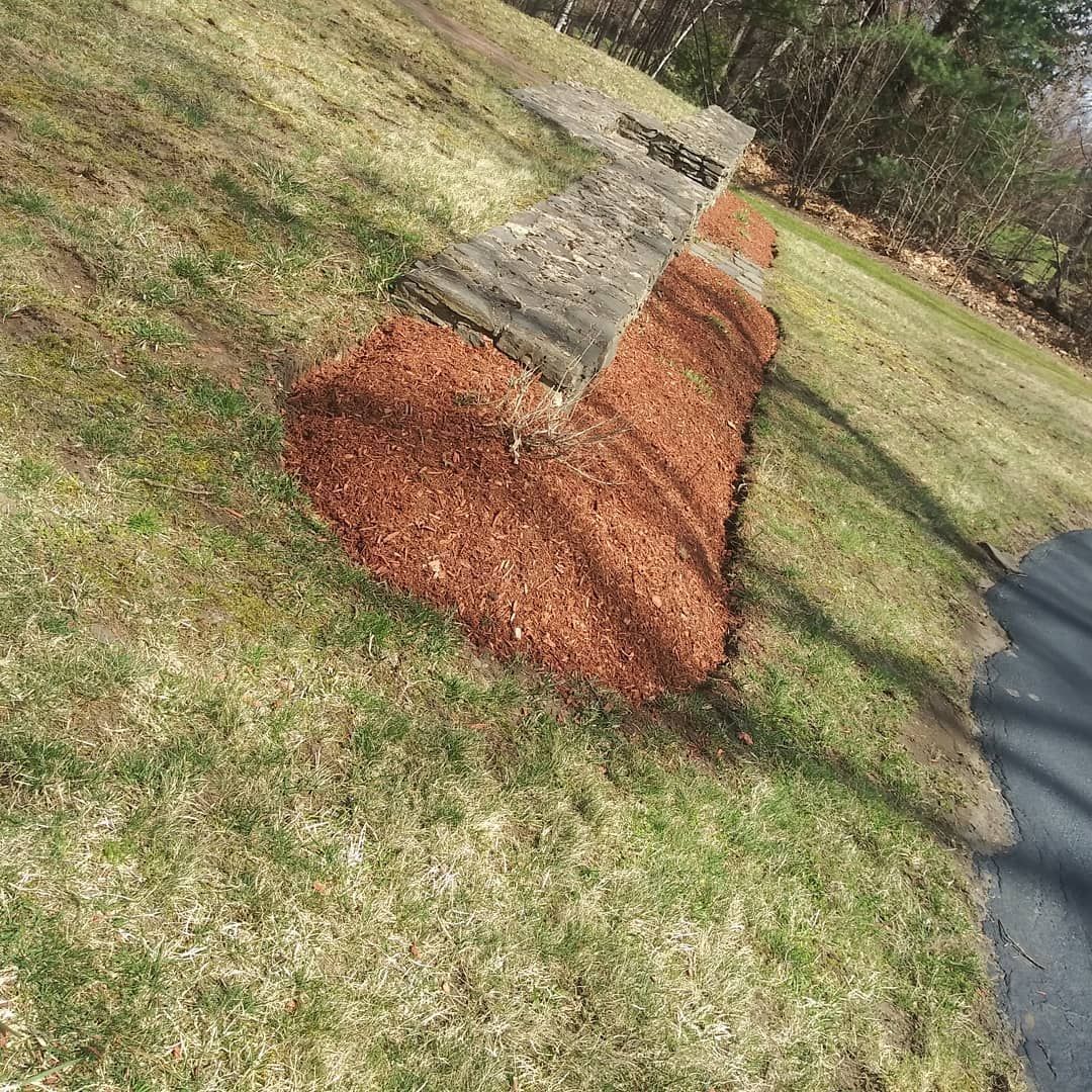 A pile of mulch is sitting on top of a grass covered field.