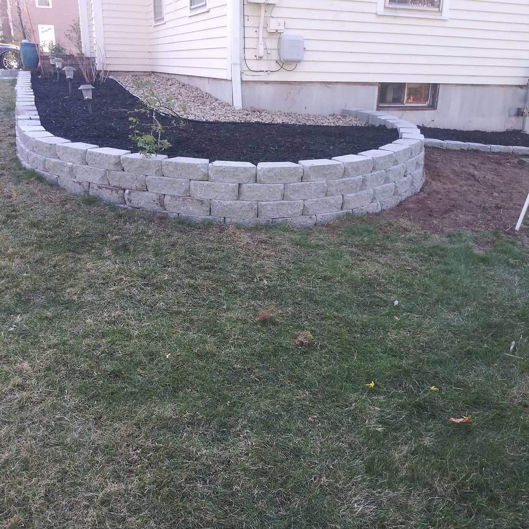 A brick wall with black mulch in front of a house.