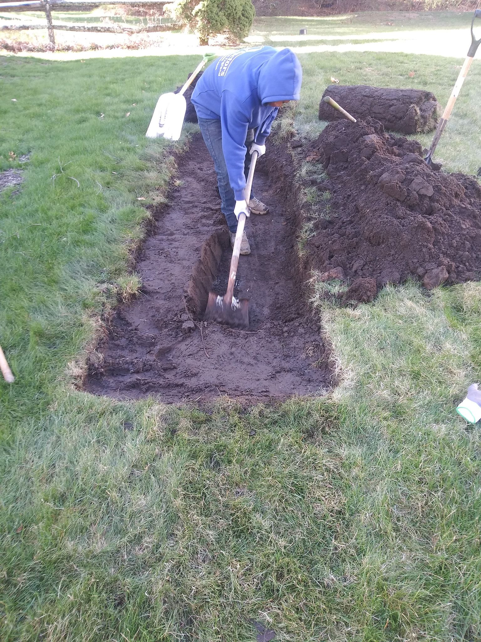 A man is digging a hole in the ground with a shovel.