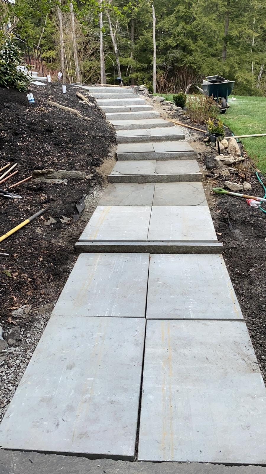 A concrete walkway with steps going up a hill.