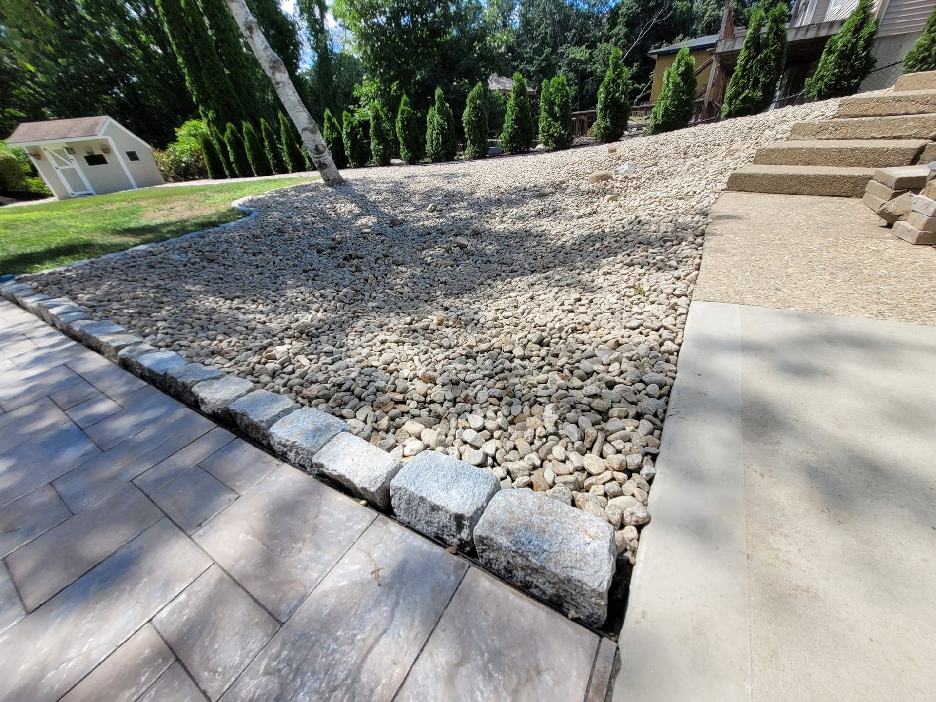 A brick walkway with gravel and steps leading to a house.