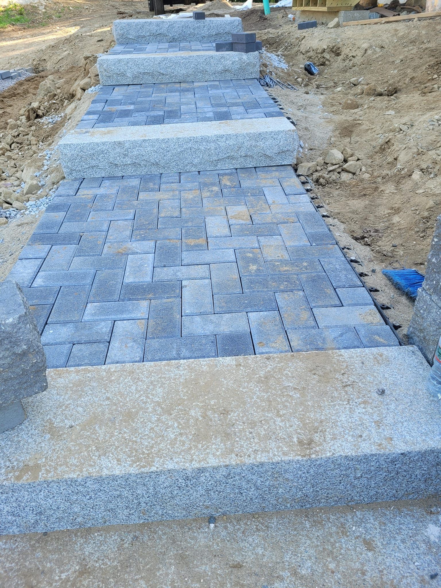A stone walkway with stairs being built in the dirt.