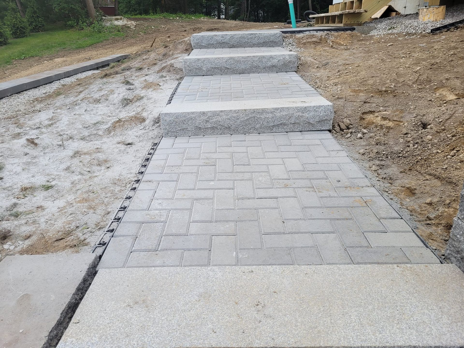 A brick walkway with steps leading up to a dirt field.