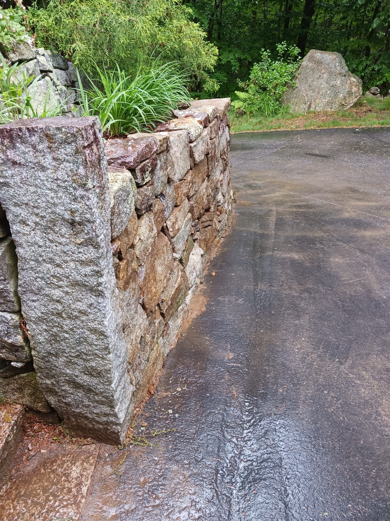 A stone wall is sitting on the side of a road.