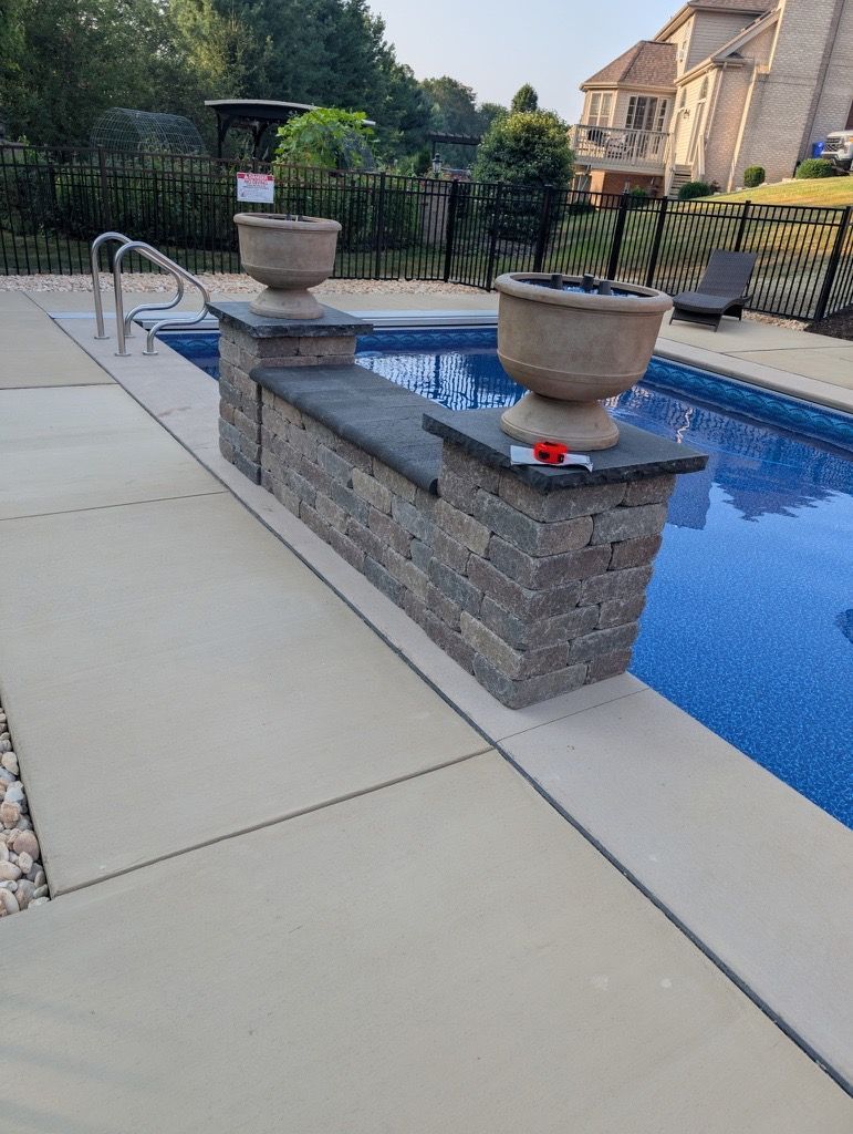 Backyard pool with stone fountain planters, blue water, and patio decking